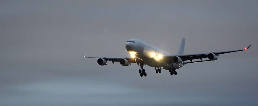Airliner on final approach with landing lights lit along with red and green position lights